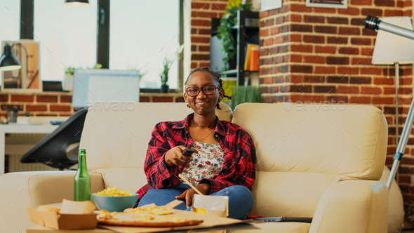 Happy woman switching channels with tv remote control