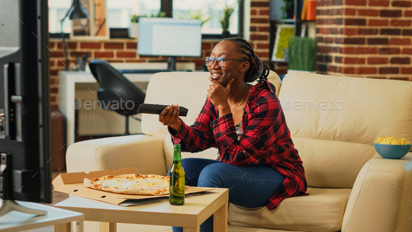 Smiling girl preparing to eat slice of pizza at tv