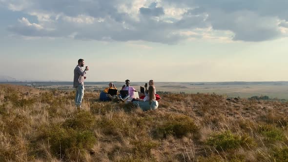 Team of Freelancers Work Outdoors in Field on Laptops Drink Coffee and Sit in Comfortable Bag Chairs alt