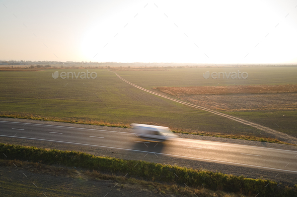 Aerial view of blurred fast moving cargo van driving on highway hauling goods.