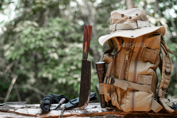 Equipment for survival bucket hat backpack hiking knife camping flashlight resting on wooden timber