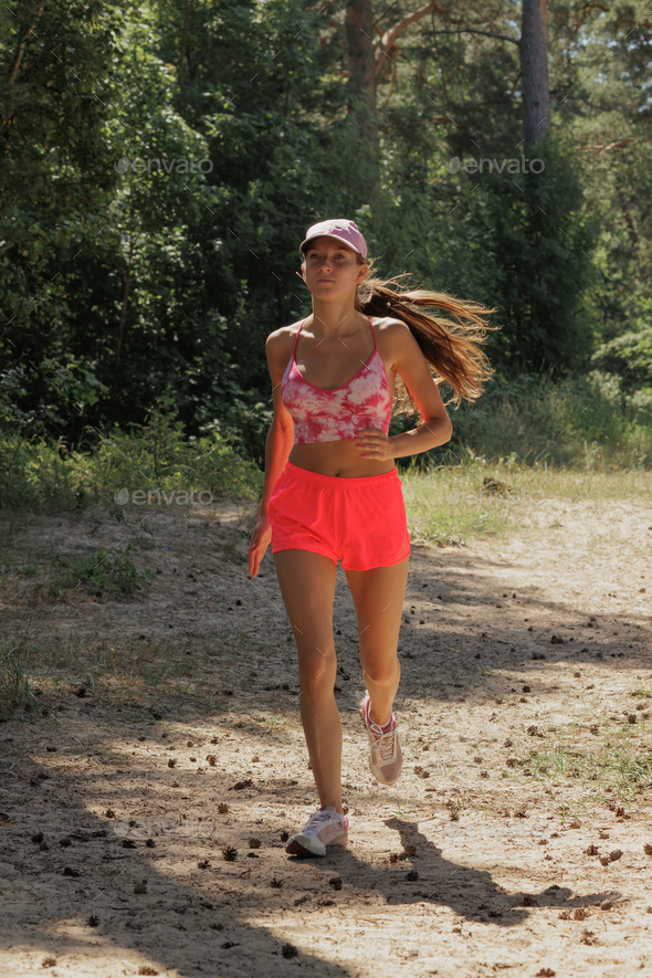 sporty woman runs in forest among trees. fitness, yoga for health of body and mental state