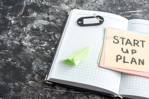 front view start up plan note on sticker inside open copybook on light gray background lesson
