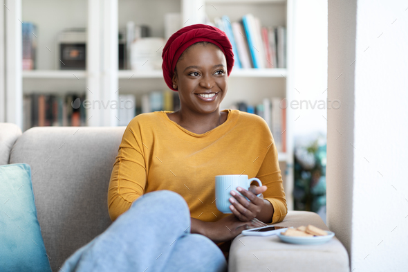 Happy pretty black woman chilling alone on couch at home