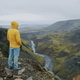Man in yellow coat on cliff edge with Haifoss waterfall in background Iceland highland - PhotoDune Item for Sale
