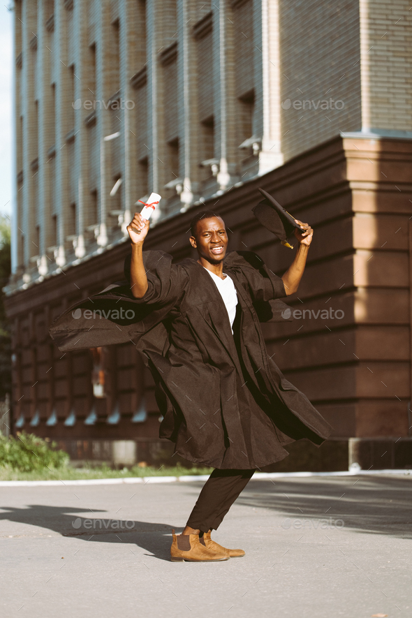 Happy afro american guy enjoying and holding diploma of education near educational establishment