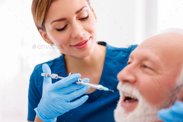 Dentist applying local anesthetic to patient