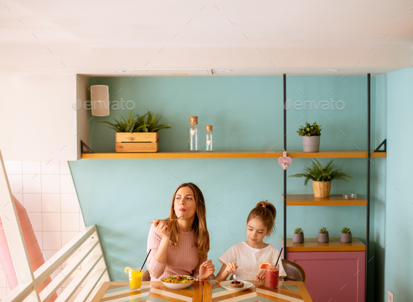 Mother and daughter having a breakfast with fresh squeezed juices in the cafe - Stock Photo - Images