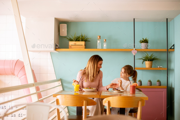 Mother and daughter having a breakfast with fresh squeezed juices in the cafe - Stock Photo - Images
