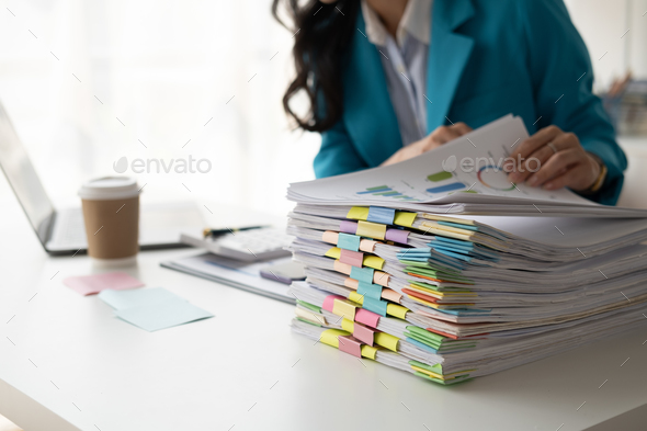 Young professional businesswoman working with stack of papers, searshing for the right file to work