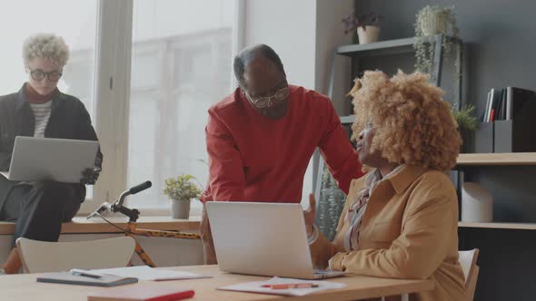 Black Man and Woman Speaking and Using Laptop in Office alt