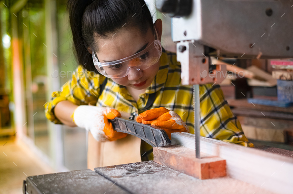 Women standing is craft working cut wood at a work bench with band saws power tools at carpenter mac