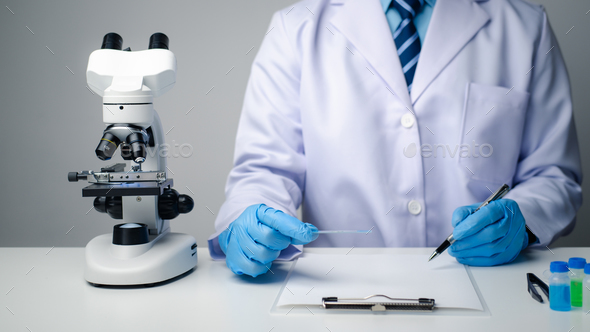 Close up view of scientist researcher taking note while testing substances in laboratory.