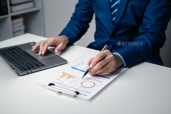Close up view of young professional businessman analysis graph and chart while using laptop in the - Stock Photo - Images