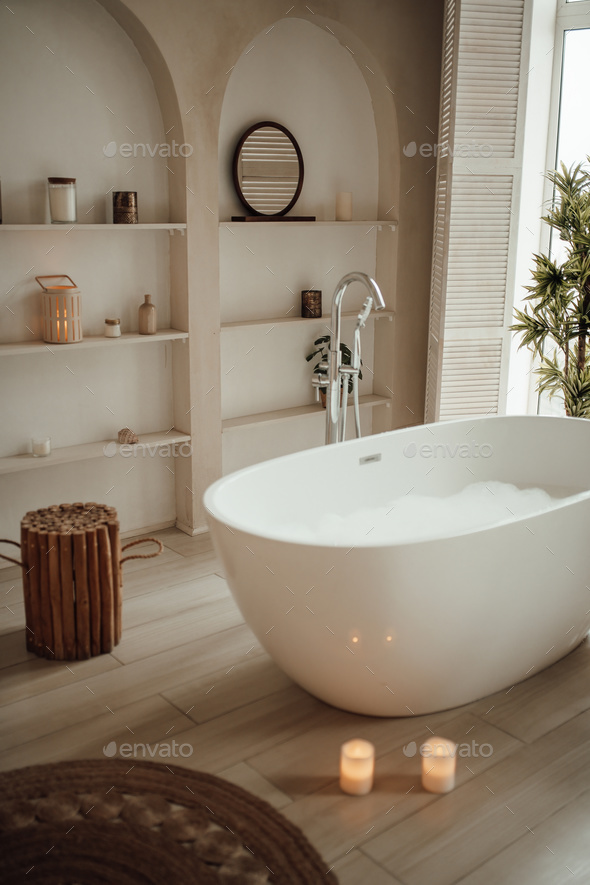 Soft native hues organic shapes look of bathroom with big window oval bathtub in neutrals tones - Stock Photo - Images