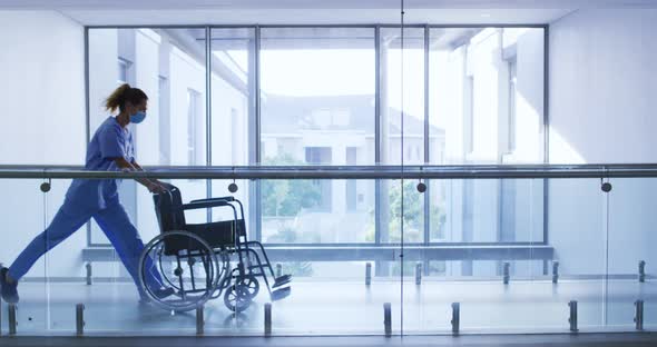 Male doctor and female health worker with wheelchair running in the corridor at hospital alt