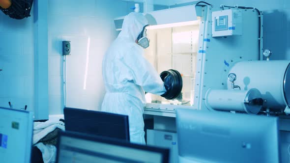 A Man in a Splash Suit is Working with a Vacuum Cabinet in the Lab alt