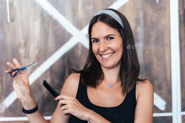 Cool hairdresser smiling and holding scissors and comb - Stock Photo - Images