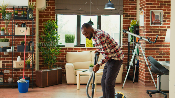 African american partner using vacuum to clean dust in living room