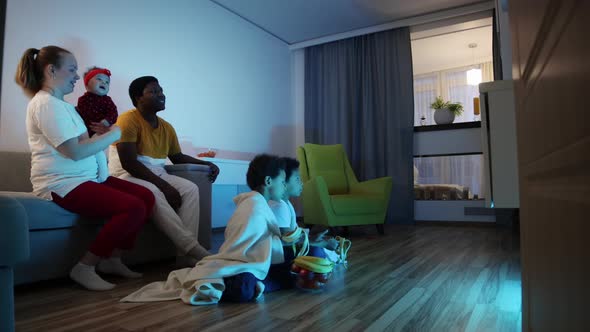 Multicultural Smiling Family Watches TV in the Room alt