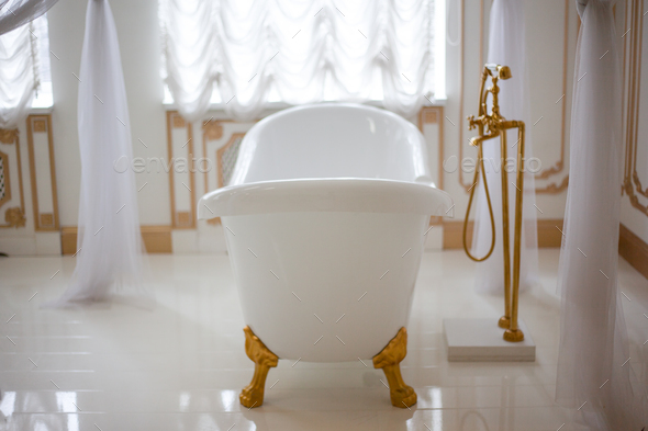White bathroom. Bathtub in baroque and rococo style. Empire and luxury. The interior is cozy and