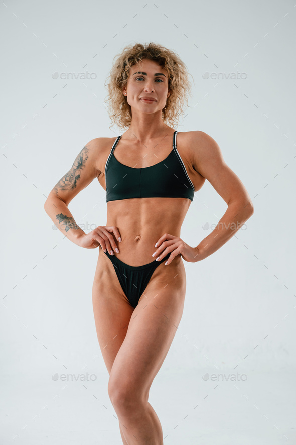 Hands on the waist, standing. Young caucasian woman with athletic