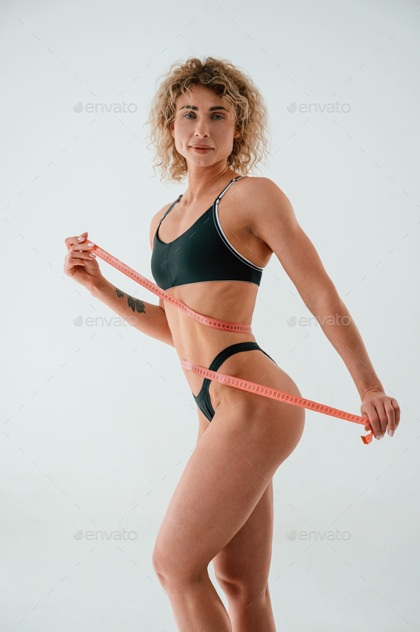 Pretty Caucasian woman measuring her waist measuring tape, Stock image