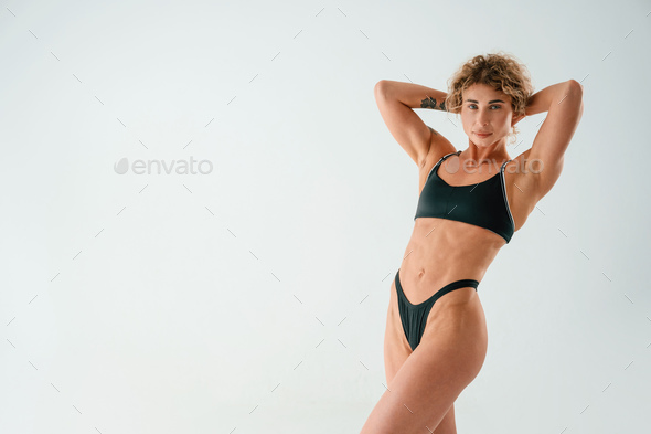 Showing abs. Young woman with slim body type is in fitness clothes in the  studio Stock Photo by mstandret
