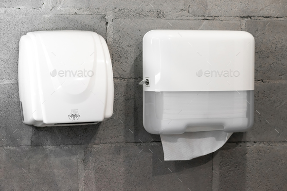 Paper towel dispenser and hand dryer on concrete wall