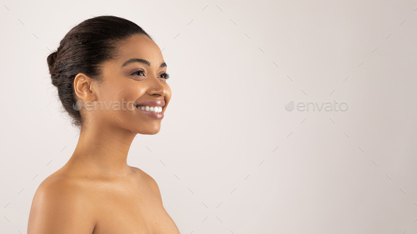 Happy millennial black woman posing topless, looking at copy space