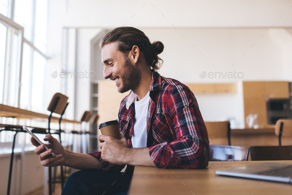 Joyful man with coffee to go browsing cell content