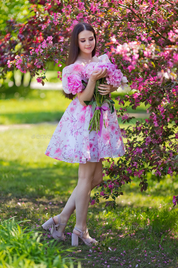 brunette with a large bouquet of peonies, in pink blooming in