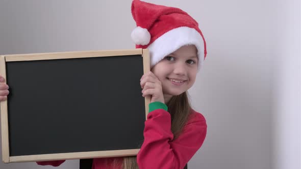 Christmas Cute Little Santa Girl Smiling Shows Blank Empty Billboard Sign alt