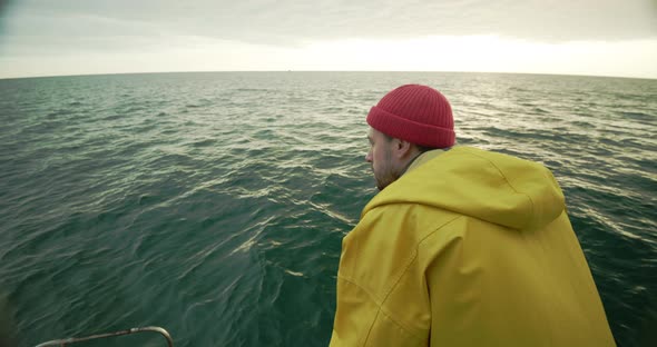 Sailor Looks at the Horizon and Into the Water Smiles on the Boat at Sunset