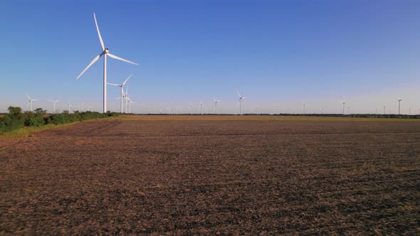 Windmills in a plowed field. Wind farm with turbine cables for wind energy.