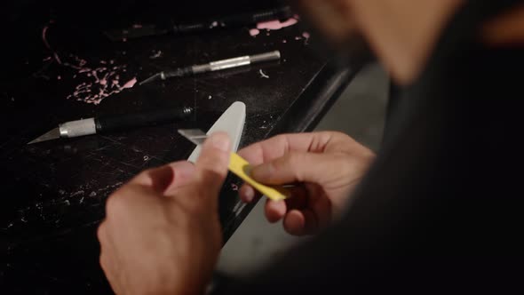 A man of Arab appearance sharpens a blade in a workshop. Sculptor, painter, needleworker. alt