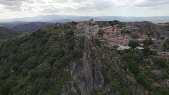 Castle of Sortelha on top of steep cliff; drone arc shot reveals landscape