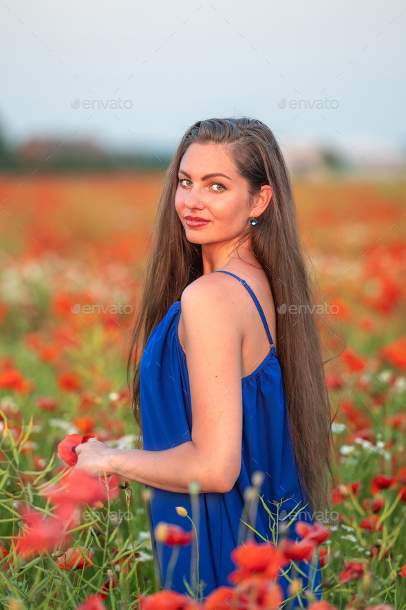 portrait of elegant young woman in poppy field in evening sunlight - Stock Photo - Images