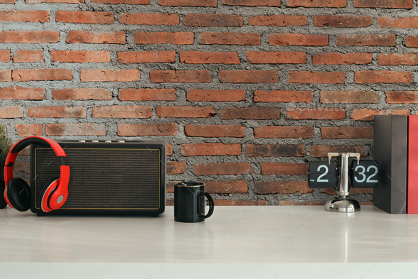 Stylish workplace with wireless speaker, headphone, vintage flip clock and coffee cup on white table