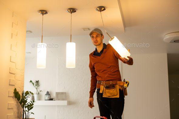 Electrician man working on exterior light, install LED replacement lamp at home. Maintenance concept