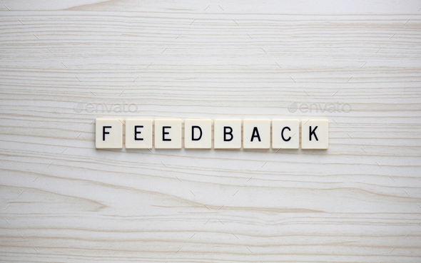 Feedback letter tiles on a wood grain background - Stock Photo - Images