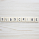 Subscribe letter tiles on a wood grain background - PhotoDune Item for Sale