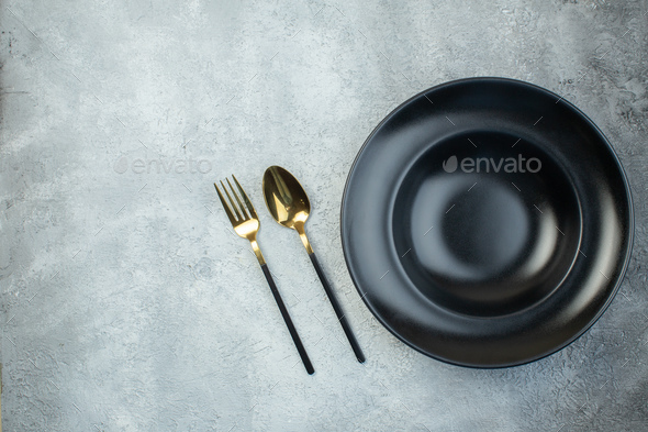 Black dinnerware set and cutlery set on isolated gray ice background with free space