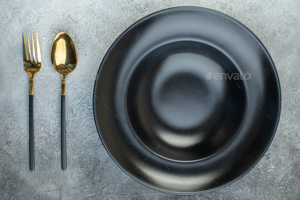 Close up shot of black dinnerware set and cutlery set on isolated gray ice background with free