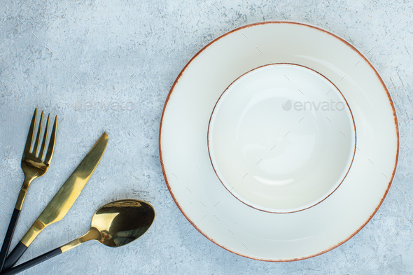 Elegant bright cutlery set and dinnerware set on isolated gray ice background with free space