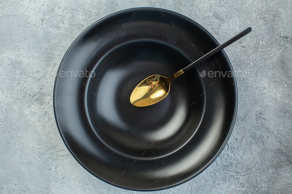 Elegant spoon on black dinnerware set on isolated gray ice background with free space