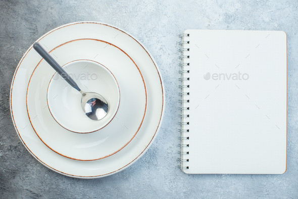 Spoon on elegant dinnerware set and notebook on gray background with distressed surface with free