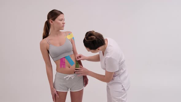 Therapist is applying kinesio tape to female body. Physiotherapy and kinesiology concepts. alt