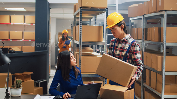 Asian guy organizing boxes with supplies on shelves Stock Photo by DC_Studio