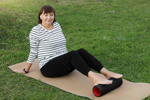 Relaxation after workout. Happy adult sportive woman in casual sportswear works out the fascia of